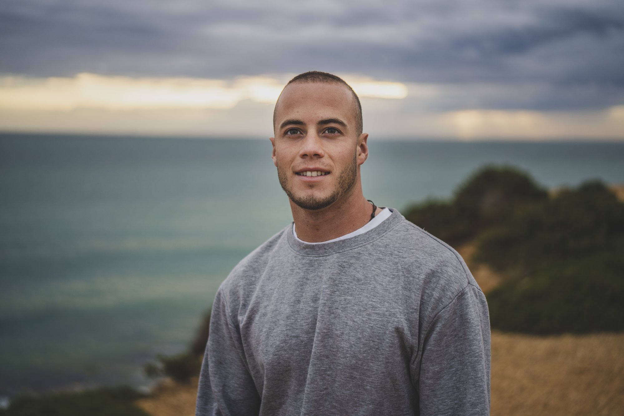 young-man-smiling-standing-cliff-near-beautiful-sea